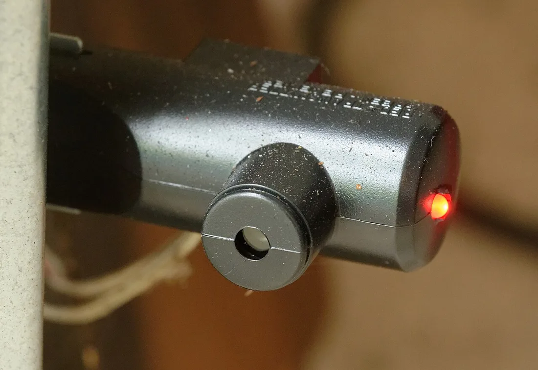 Close view of a garage door safety sensor with a red indicator light