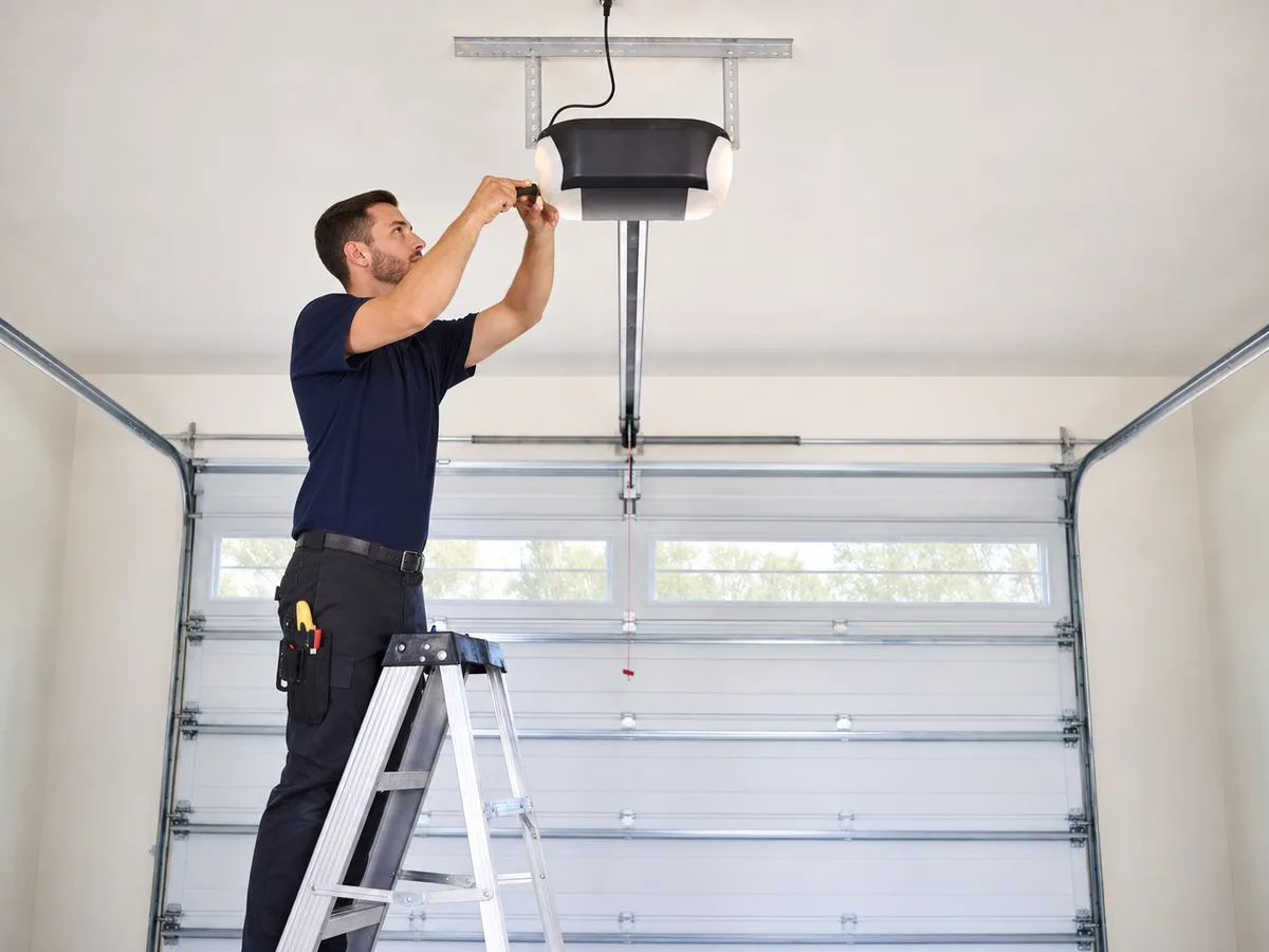 Technician servicing a ceiling-mounted residential garage door opener