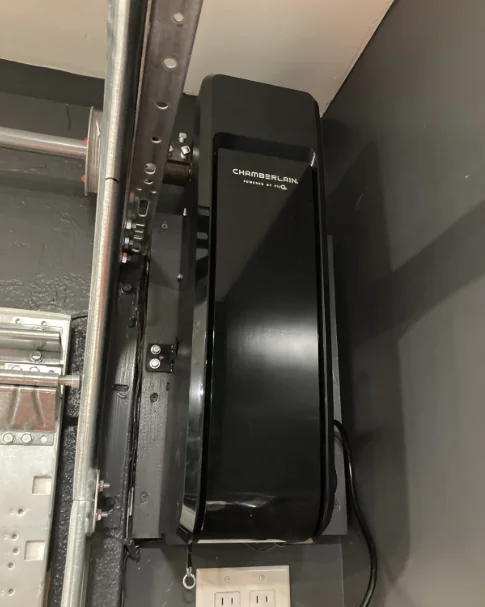 Chamberlain side-mount opener installed beside a garage door track against a gray wall
